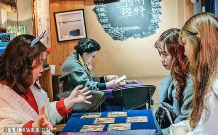 Một thầy bói nữ đang xem bói bài Taro cho hai khách hàng là nữ giới.