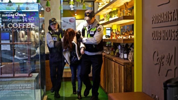 Cảnh sát Hàn Quốc đang dìu một cô gái say rượu trong club đi ra.