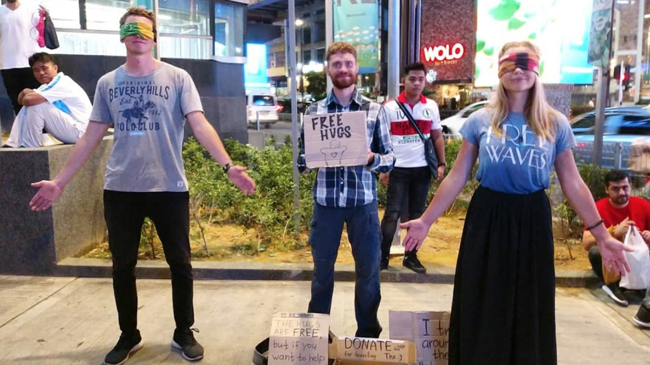 Một nhóm Tây ba lô với tấm biển Free Hug (ôm miễn phí) trong khu phố du lịch.